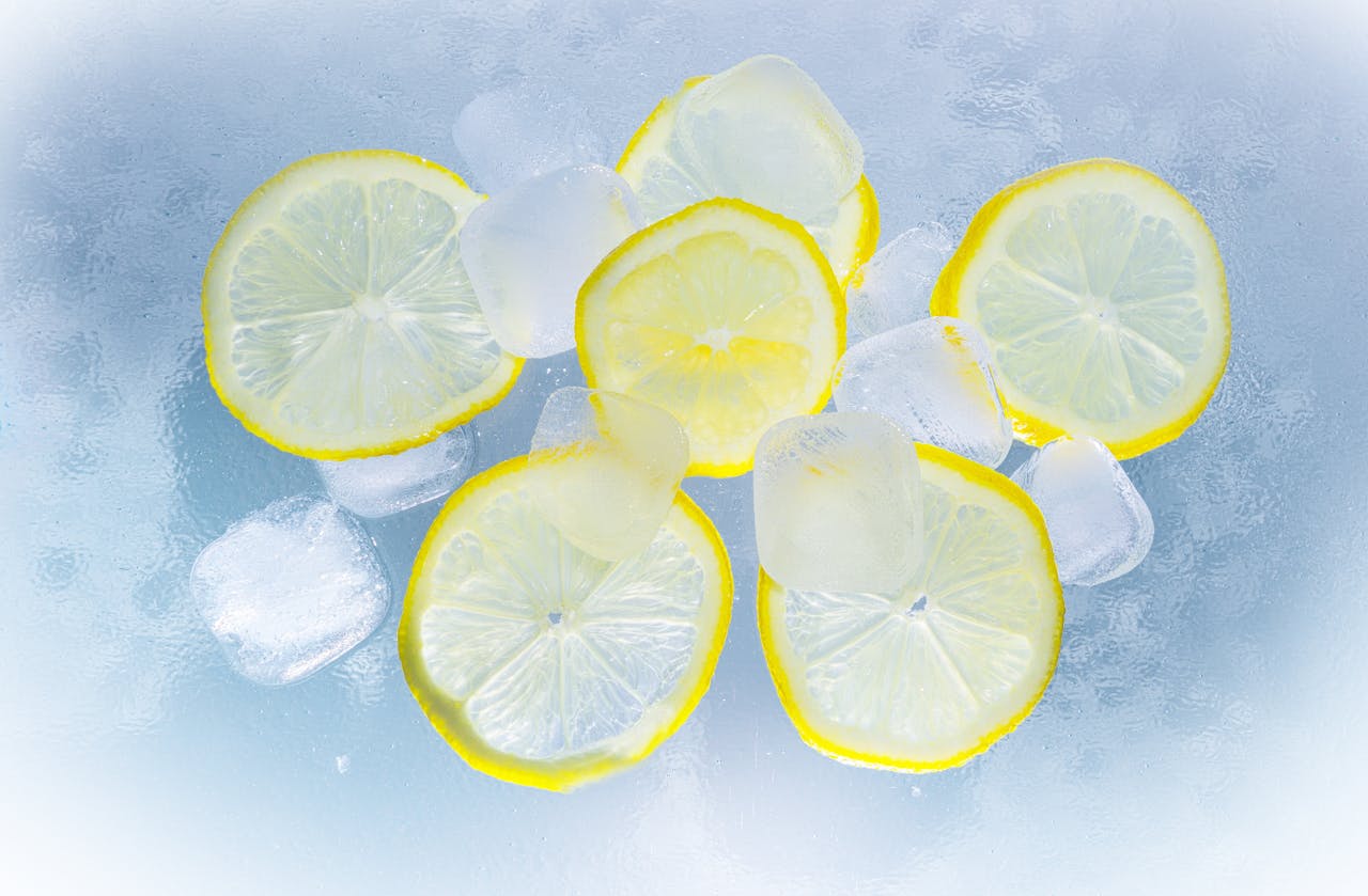 Fresh lemon slices and ice cubes on a cool surface, perfect for refreshment.