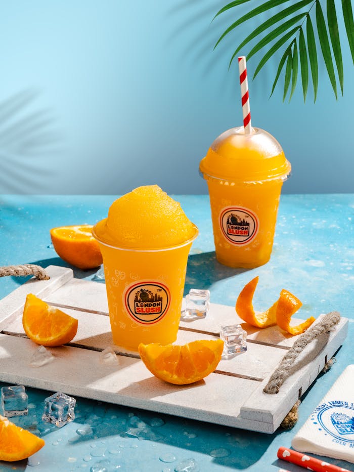 Cool down with vibrant orange slushies served with fresh orange slices and ice cubes on a summer day.
