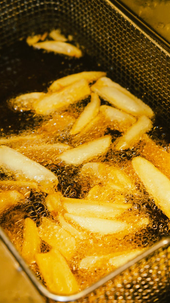 Golden brown French fries frying in hot oil, capturing a classic fast food moment.