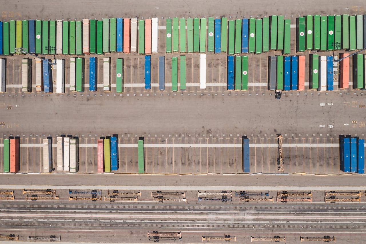 A birds-eye view of colorful shipping containers at a railway logistics yard.