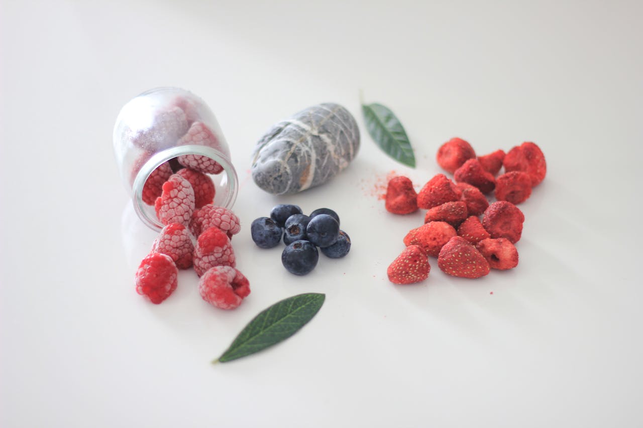 Close-up of frozen raspberries, blueberries, and strawberries on a white surface.